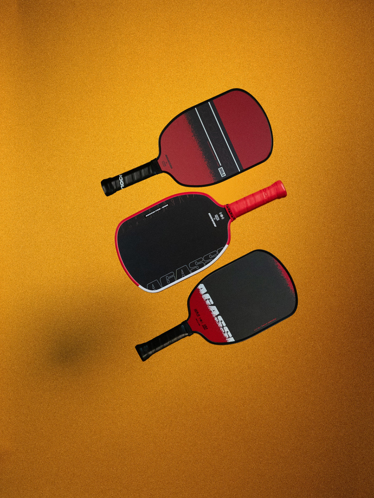 Three pickleball paddles on a yellow background